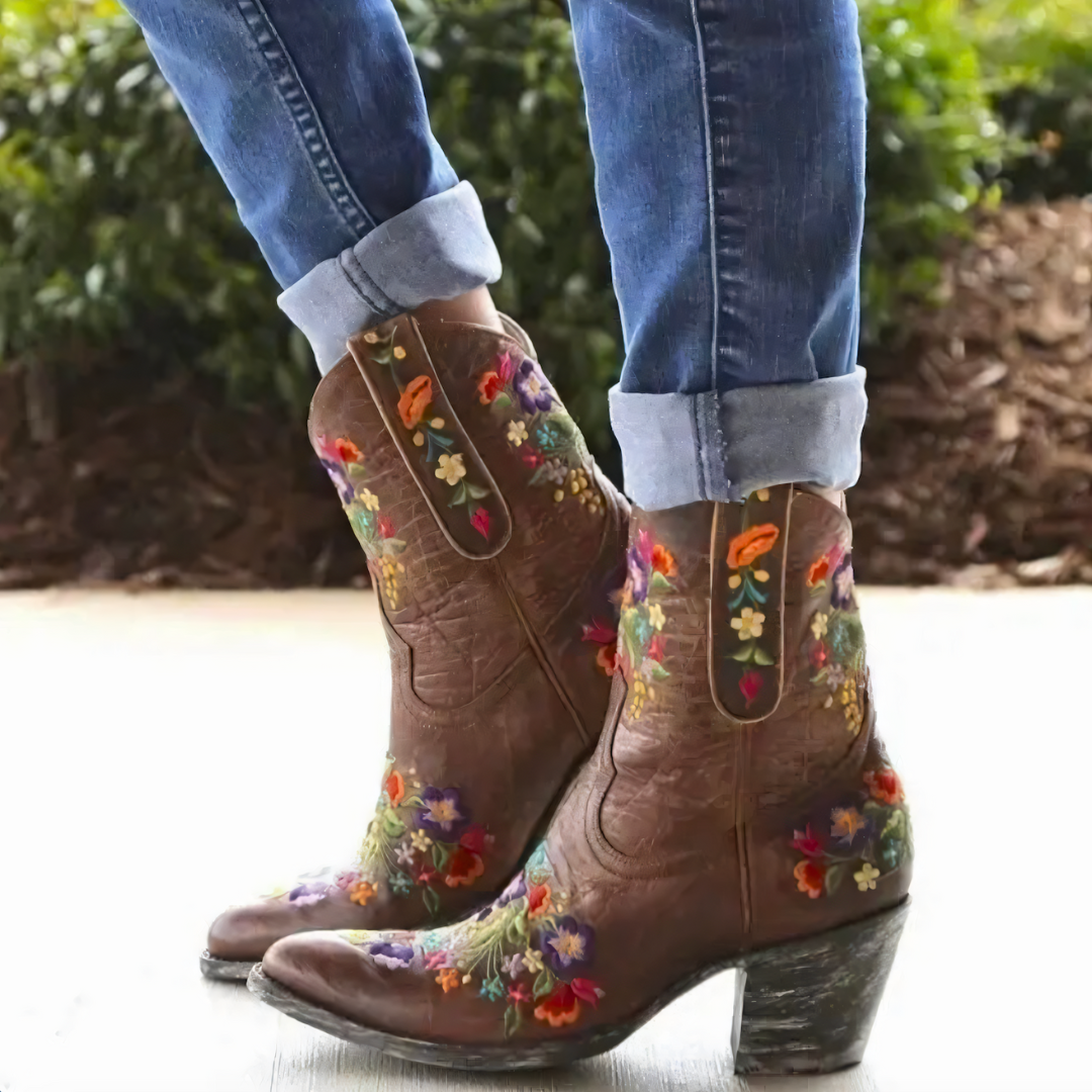 Bruine leren cowboylaarzen met kleurrijke bloemenborduursels, gedragen met opgerolde spijkerbroek. Perfect voor bohemian en westerse mode.