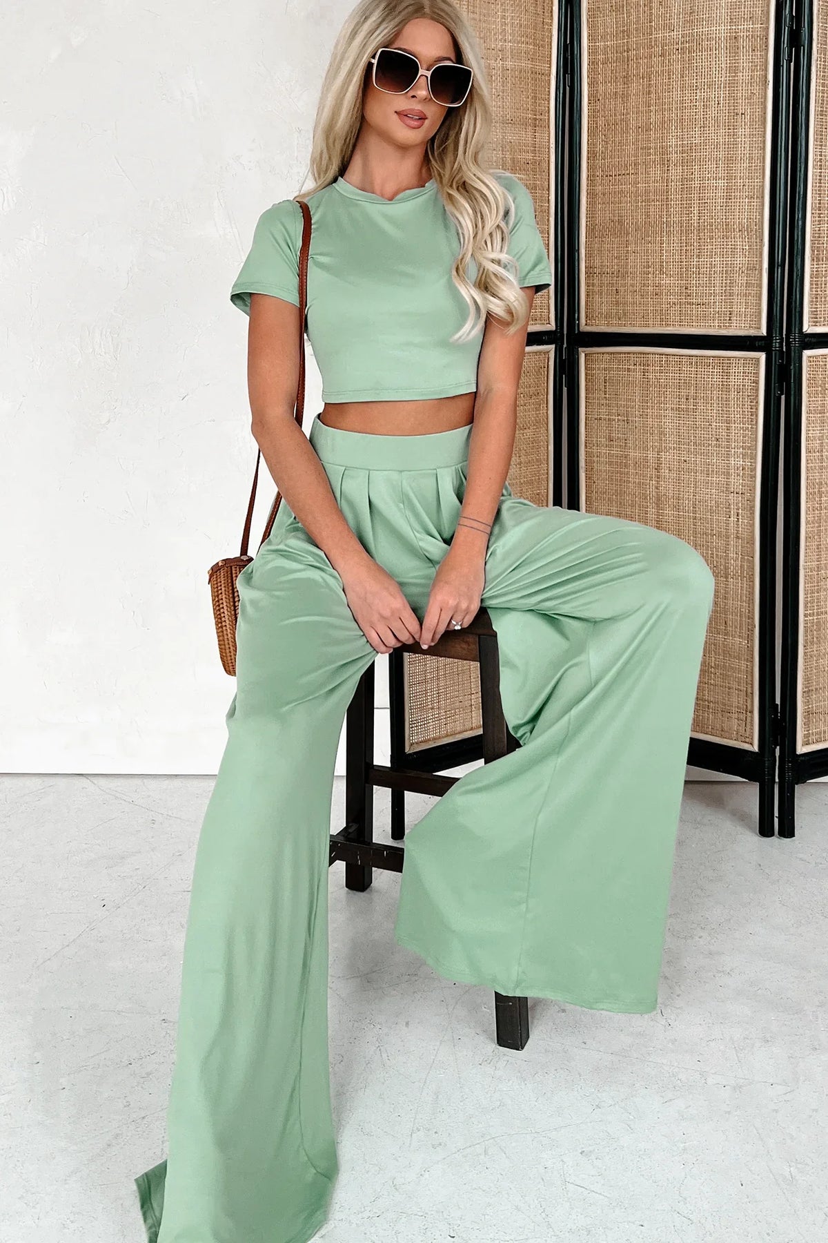 Model draagt elegante comfortabele 2 delige set met top met korte mouwen en wijde broek satijn linnen licht groen