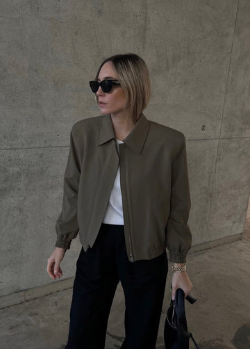 Model draagt stijlvolle donkergroene cropped tussenjas met handtas
